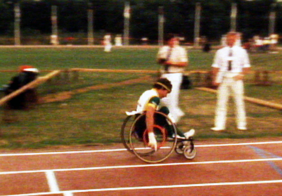 Peter Trotter saets off on the final leg of the 4x400m relay at the 1984 summer Paralympics. The Australian team finished third, some distance behind the first two teams, but still under the previous world record. This image is a still from a film made by Donald Worley about Australia's participation at the 1984 Summer Paralympics in Stoke Mandeville, England.